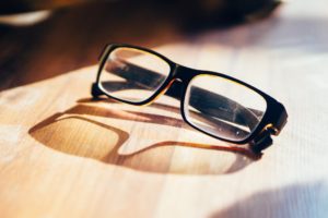 pair of eye glasses sitting on a wood desk